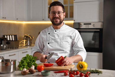 Photo of Professional chef cutting bell pepper at table in kitchen