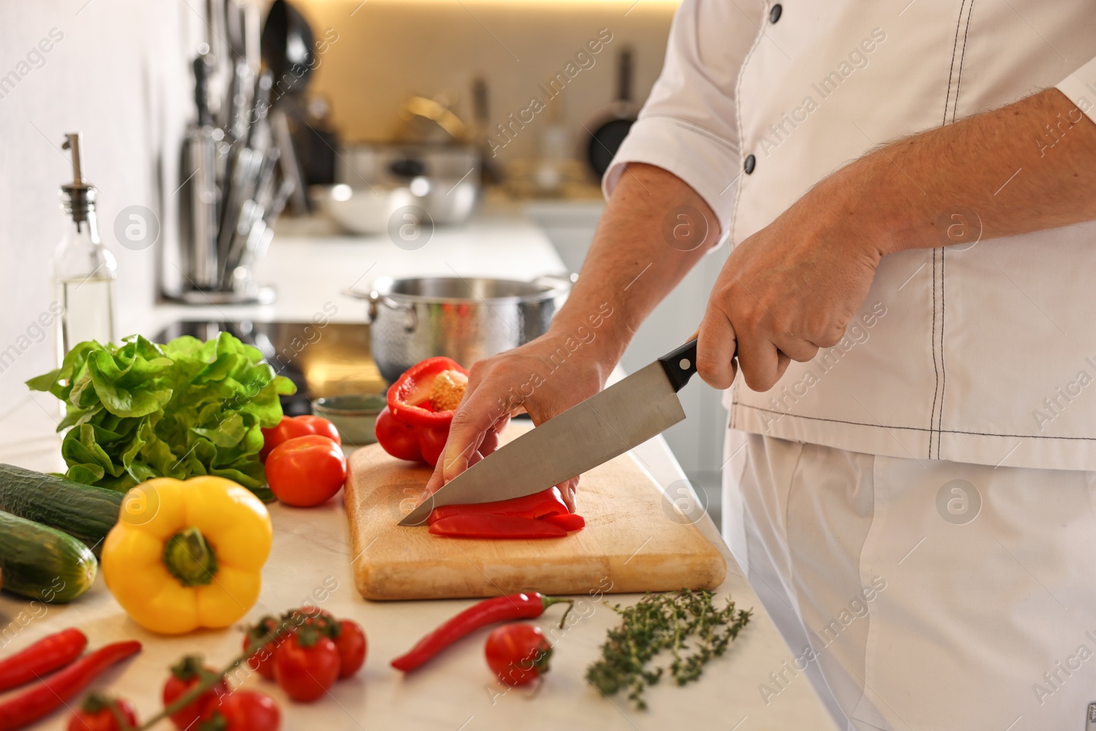 Photo of Professional chef cutting bell pepper at counter in kitchen, closeup