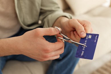 Photo of Man cutting his credit card indoors, closeup