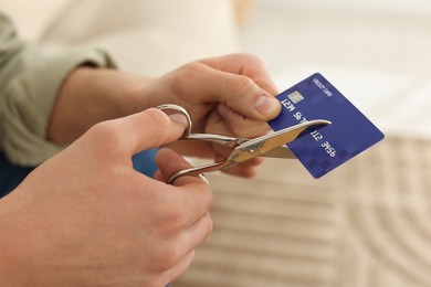 Photo of Man cutting his credit card indoors, closeup