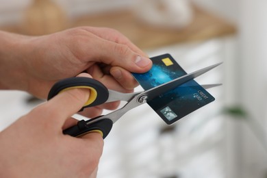 Photo of Man cutting his credit card indoors, closeup