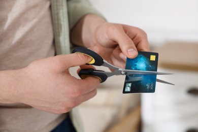 Photo of Man cutting his credit card indoors, closeup