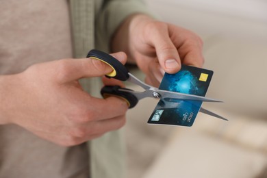 Photo of Man cutting his credit card indoors, closeup