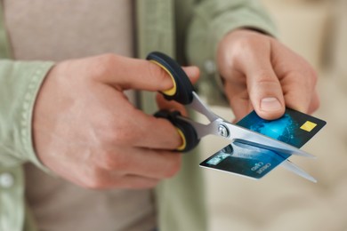 Photo of Man cutting his credit card indoors, closeup