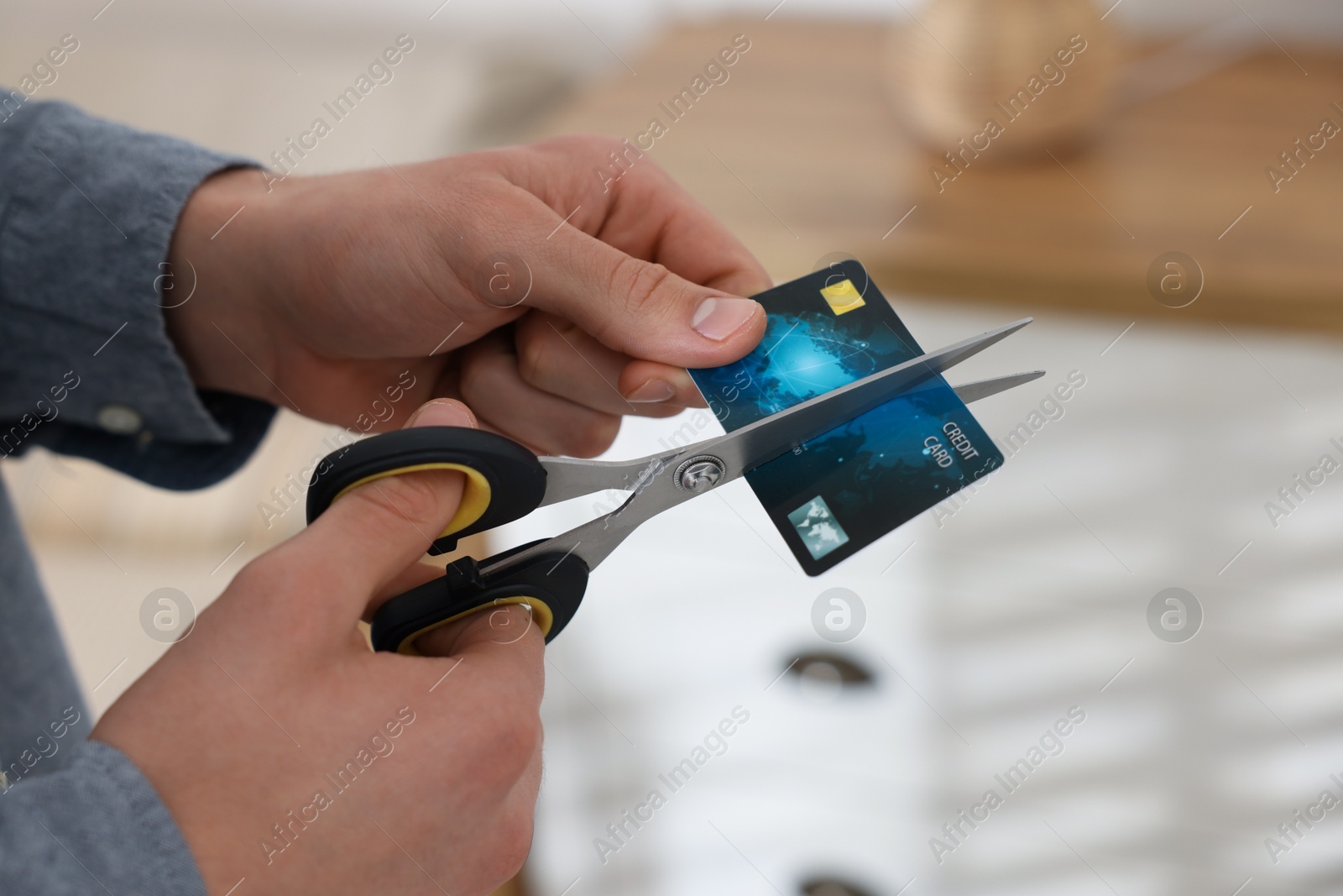 Photo of Man cutting his credit card indoors, closeup