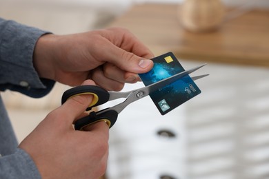 Photo of Man cutting his credit card indoors, closeup