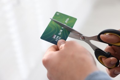 Photo of Man cutting his credit card indoors, closeup