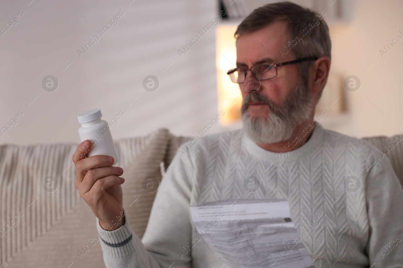 Photo of Senior man with bottle of pills and instruction at home, selective focus