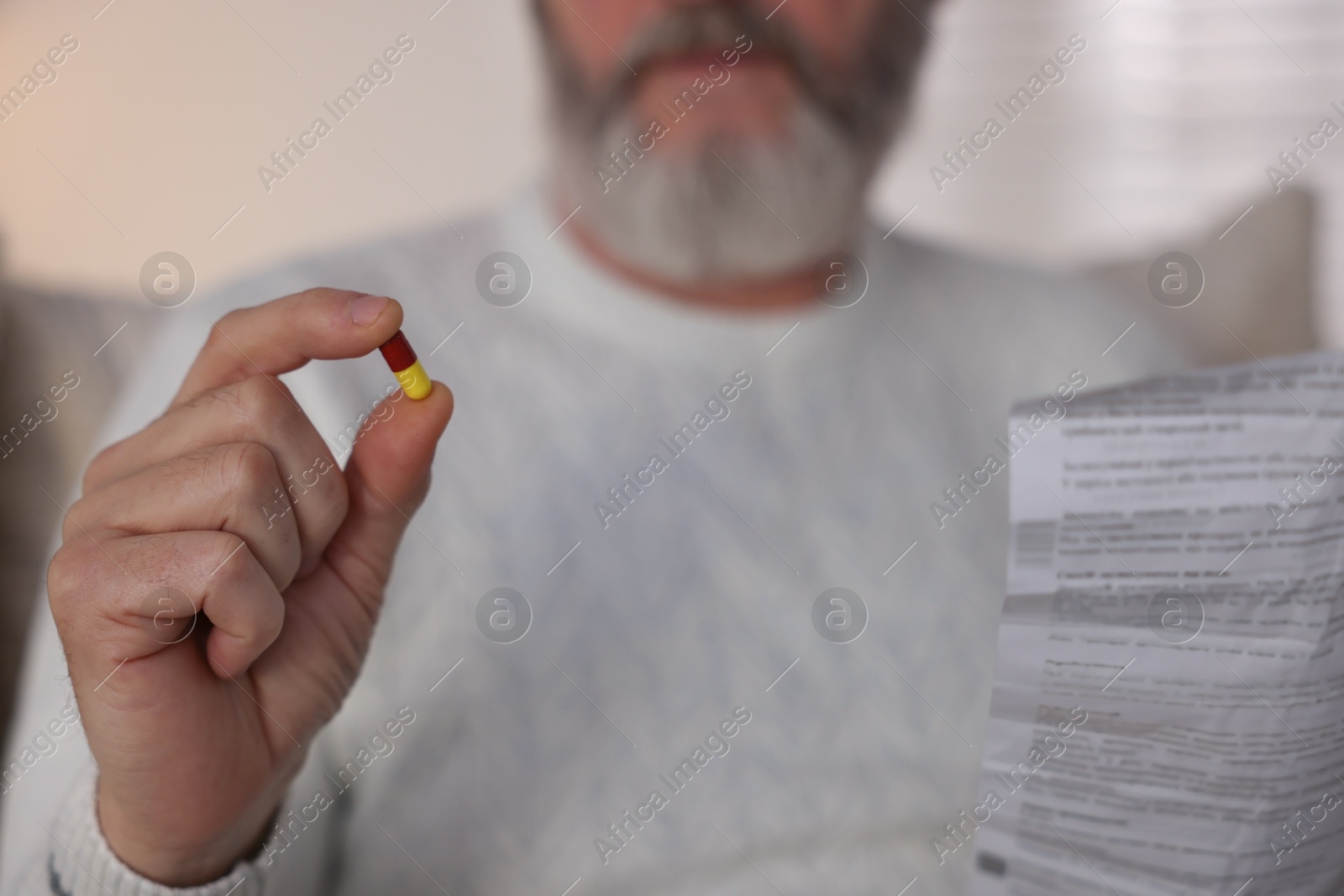 Photo of Senior man with pill and instruction at home, closeup