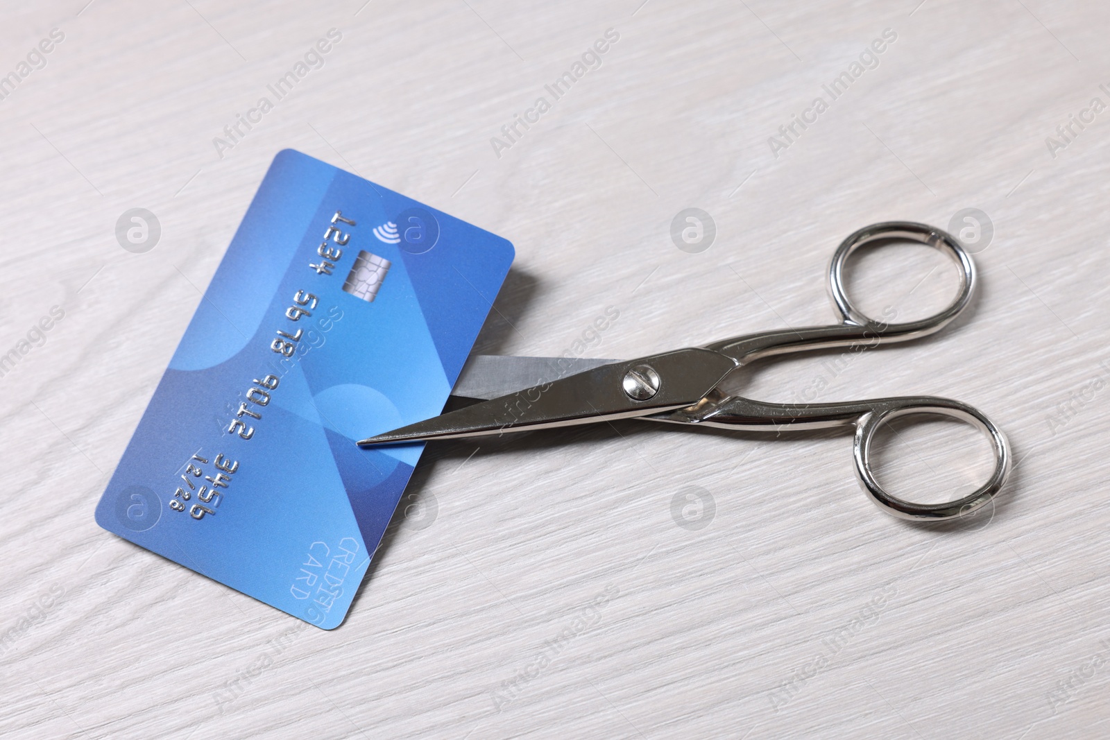 Photo of Credit card and scissors on white wooden table, above view