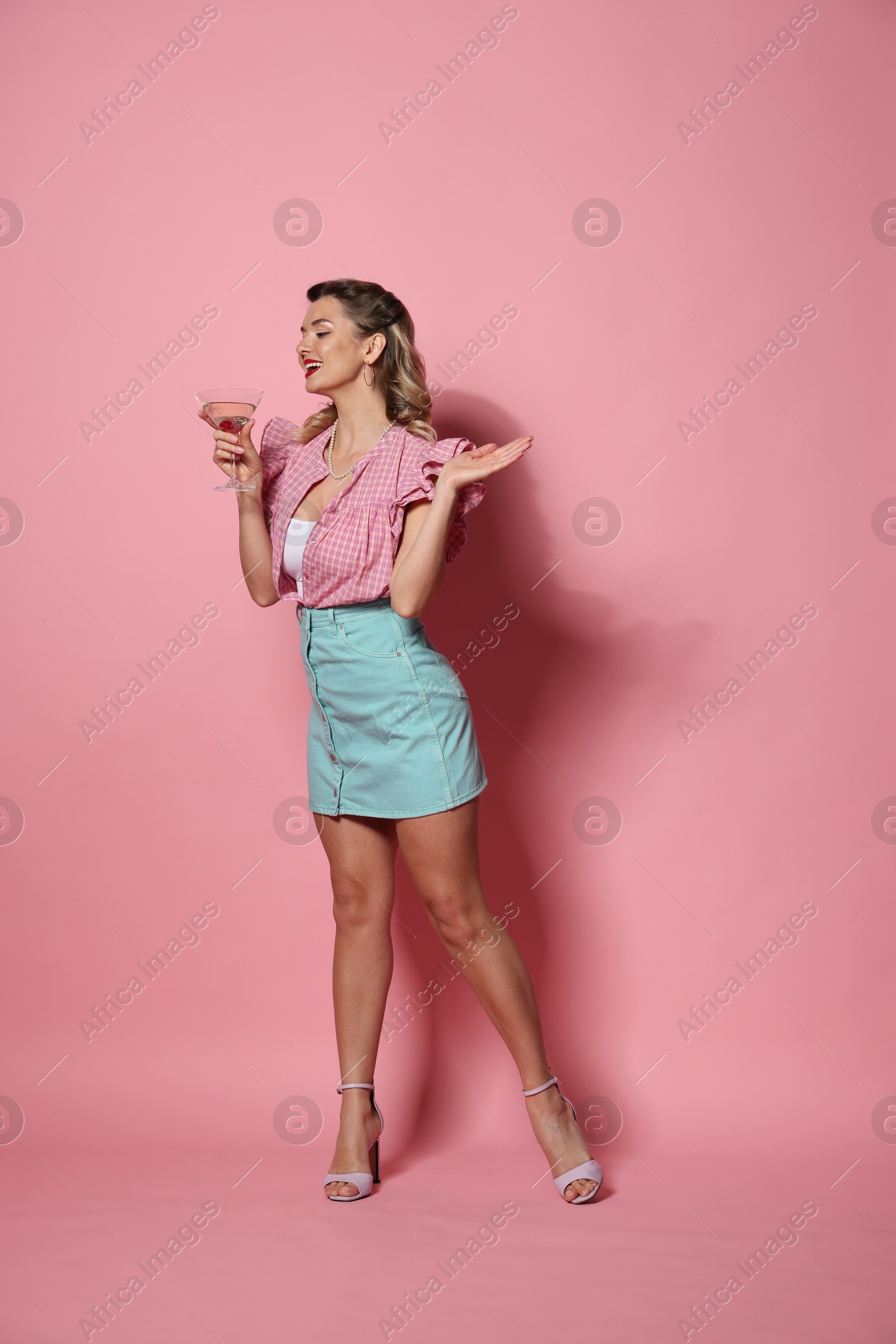 Photo of Happy pin-up woman with cocktail on pink background