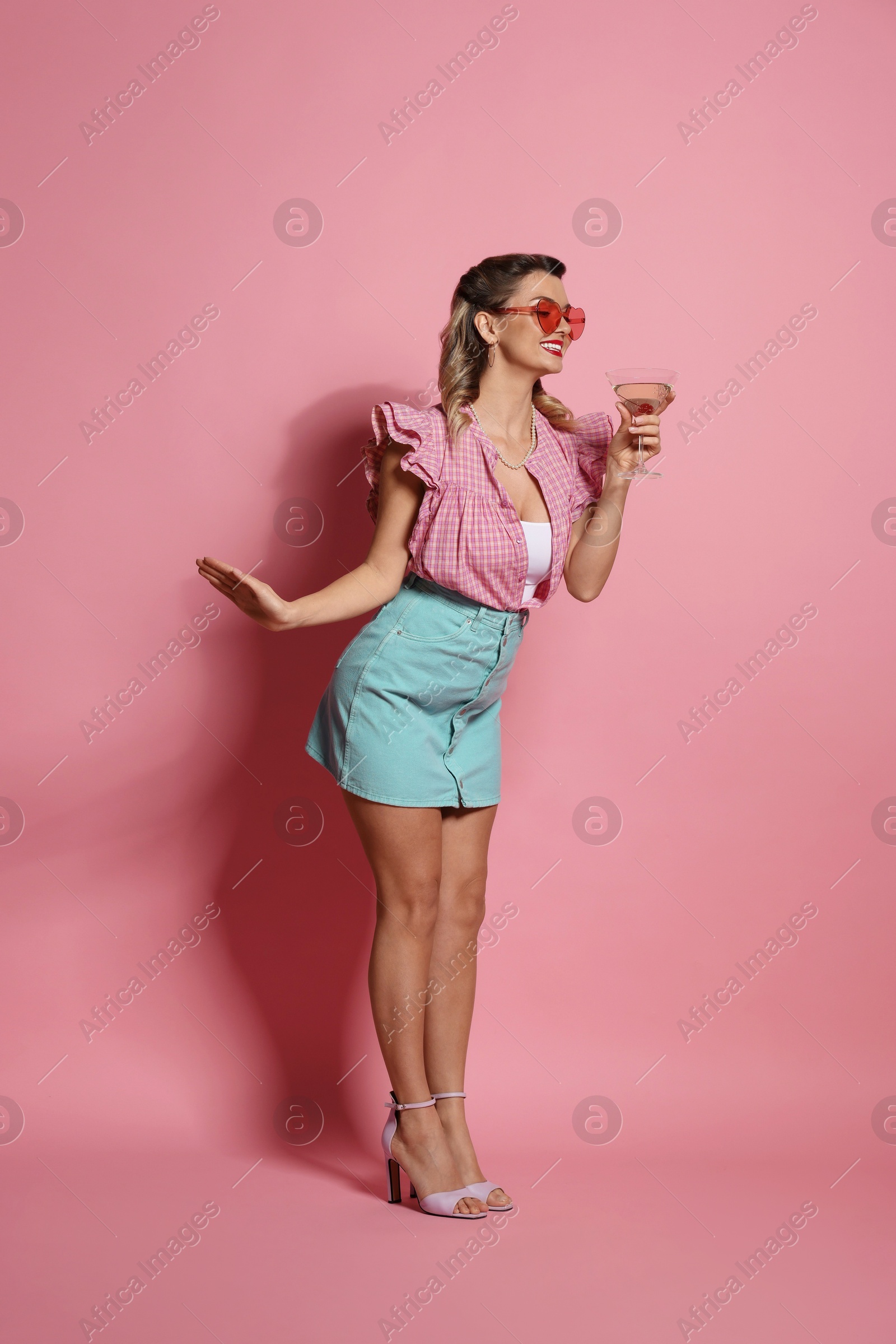 Photo of Happy pin-up woman with cocktail on pink background