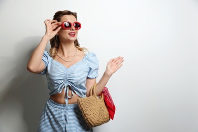 Photo of Happy pin-up woman in sunglasses on light background. Space for text