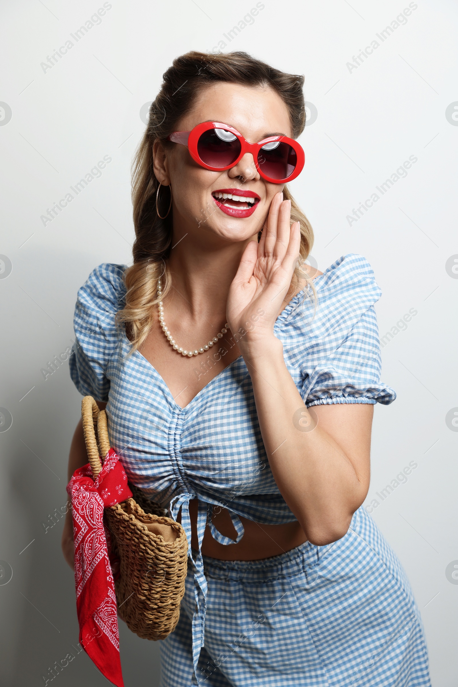 Photo of Happy pin-up woman in sunglasses on light background