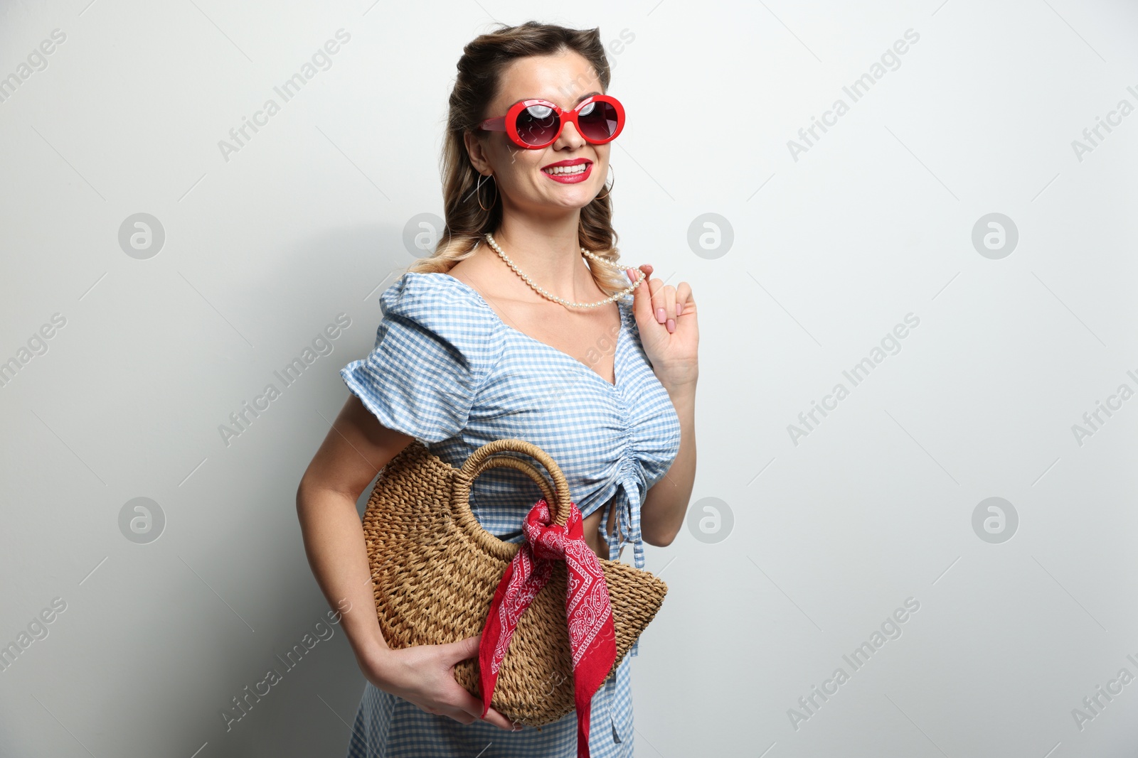 Photo of Happy pin-up woman in sunglasses on light background