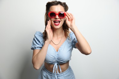 Photo of Portrait of happy pin-up woman in sunglasses on light background