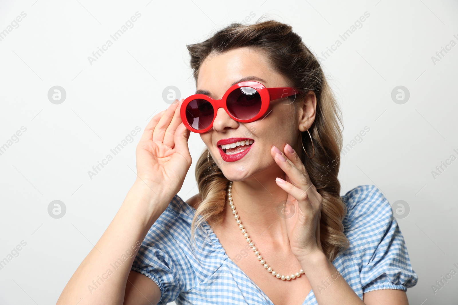 Photo of Portrait of happy pin-up woman in sunglasses on light background