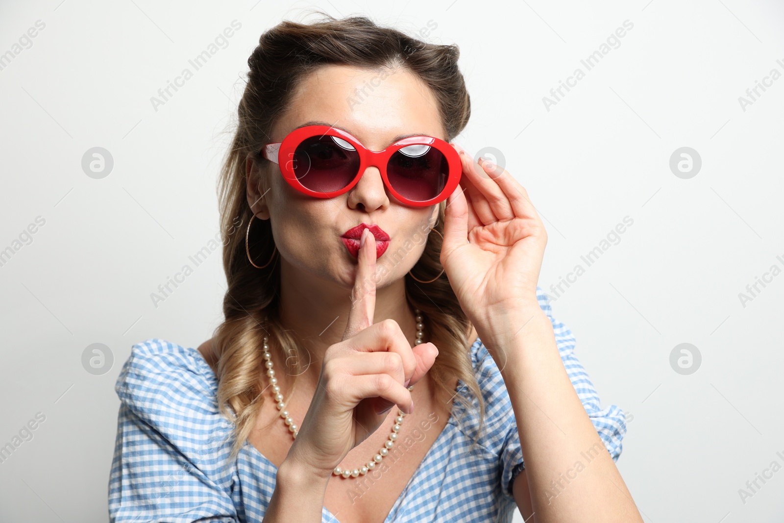 Photo of Portrait of beautiful pin-up woman showing hush gesture on light background