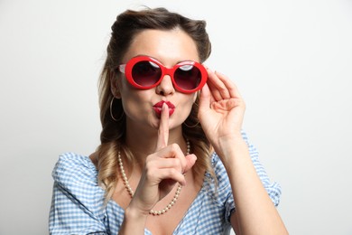 Photo of Portrait of beautiful pin-up woman showing hush gesture on light background