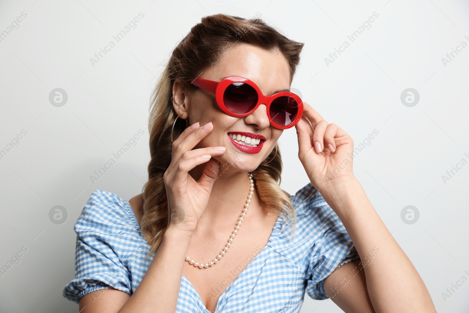 Photo of Portrait of happy pin-up woman in sunglasses on light background