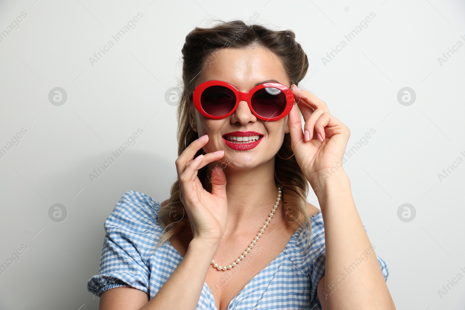 Photo of Portrait of happy pin-up woman in sunglasses on light background