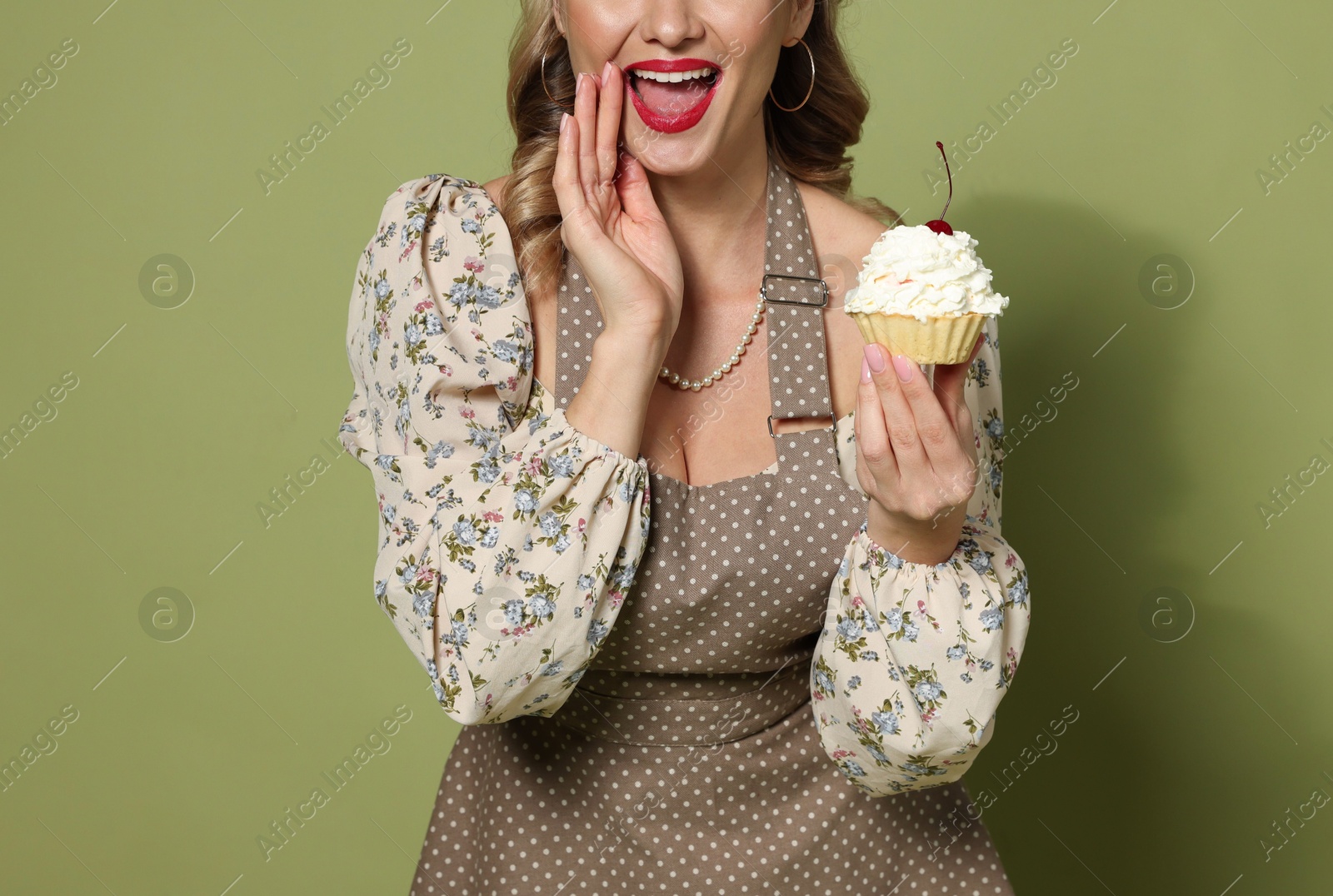 Photo of Excited woman with cupcake on green background, closeup. Pin-up vibes