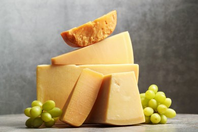 Photo of Different types of cheese and grapes on grey table