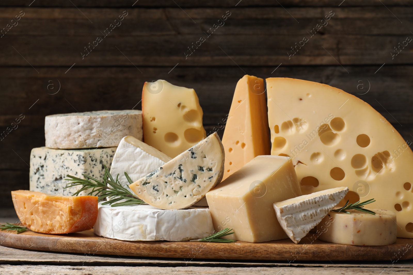 Photo of Different types of cheese and rosemary on wooden table