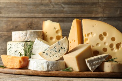 Photo of Different types of cheese and rosemary on wooden table