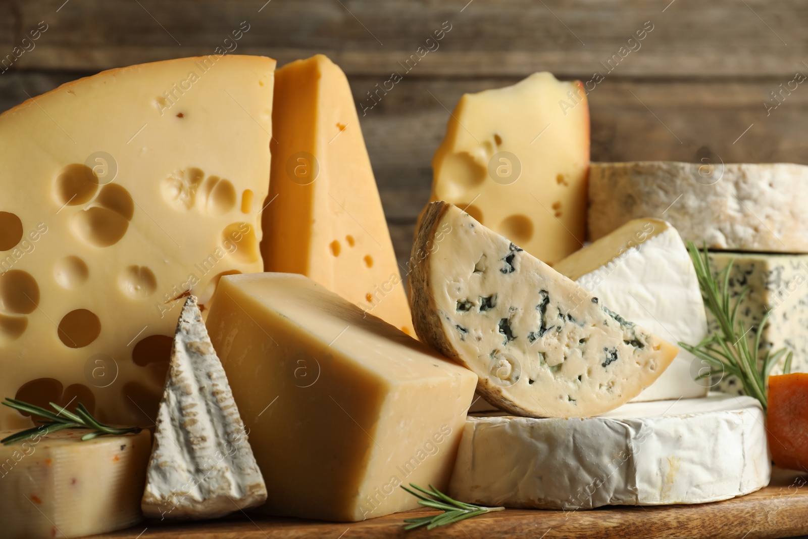 Photo of Different types of cheese and rosemary on table, closeup