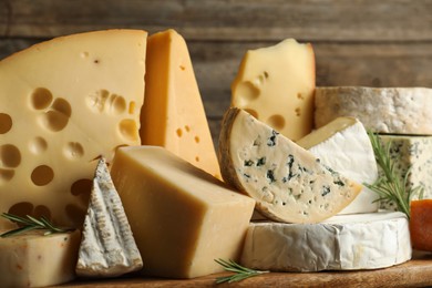 Photo of Different types of cheese and rosemary on table, closeup