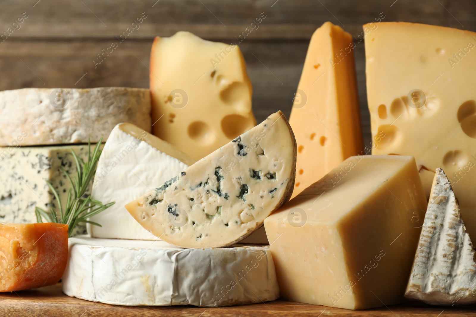 Photo of Different types of cheese and rosemary on table, closeup