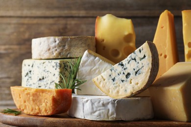 Photo of Different types of cheese and rosemary on table, closeup