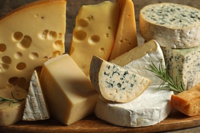 Photo of Different types of cheese and rosemary on table, closeup