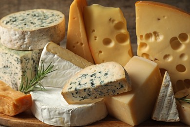 Photo of Different types of cheese and rosemary on table, closeup