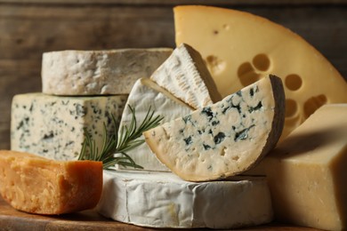 Photo of Different types of cheese and rosemary on table, closeup