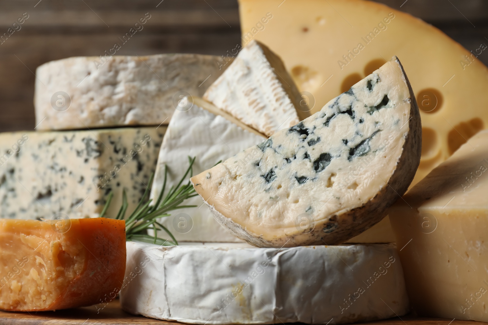 Photo of Different types of cheese and rosemary on table, closeup