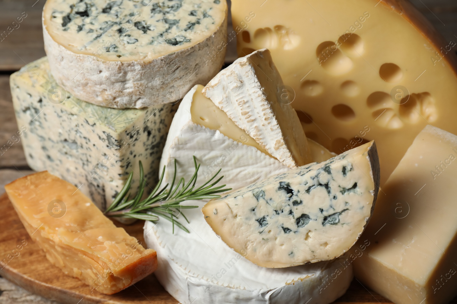 Photo of Different types of cheese and rosemary on table, closeup