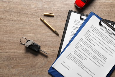 Photo of Car key, model and purchase agreement on wooden table, flat lay. Buying auto