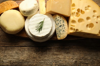 Photo of Different types of cheese on wooden table, top view. Space for text