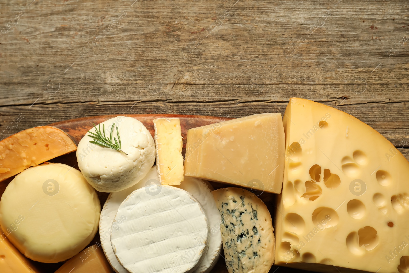 Photo of Different types of cheese on wooden table, top view. Space for text