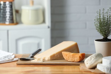 Photo of Different types of cheese, slicer and potted thyme on wooden table indoors