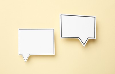 Photo of Blank speech bubbles on beige background, top view. Space for text