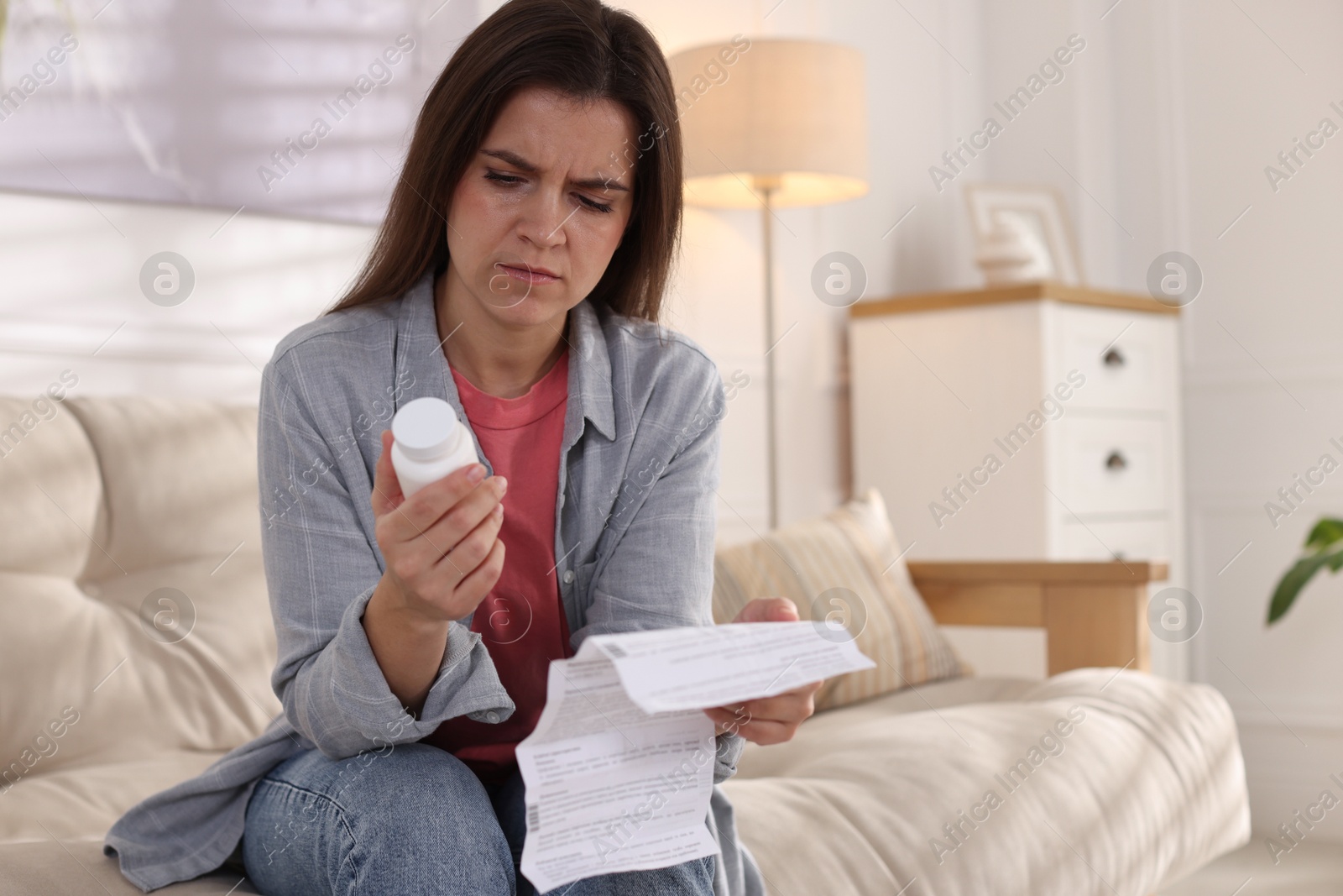 Photo of Woman with pills and medical instruction on sofa at home, space for text