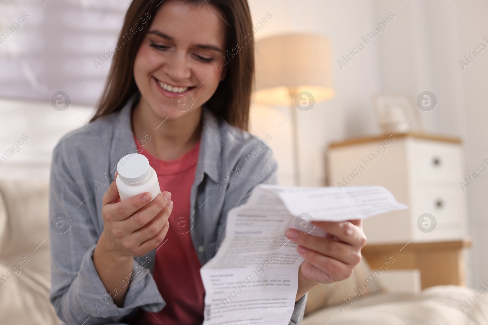 Photo of Woman with pills and medical instruction on sofa at home