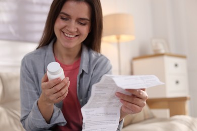 Photo of Woman with pills and medical instruction on sofa at home