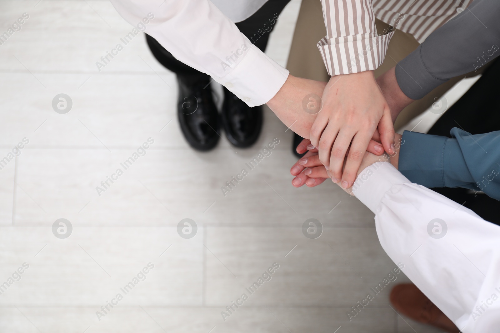 Photo of Business concept. Group of people stacking hands indoors, above view. Space for text