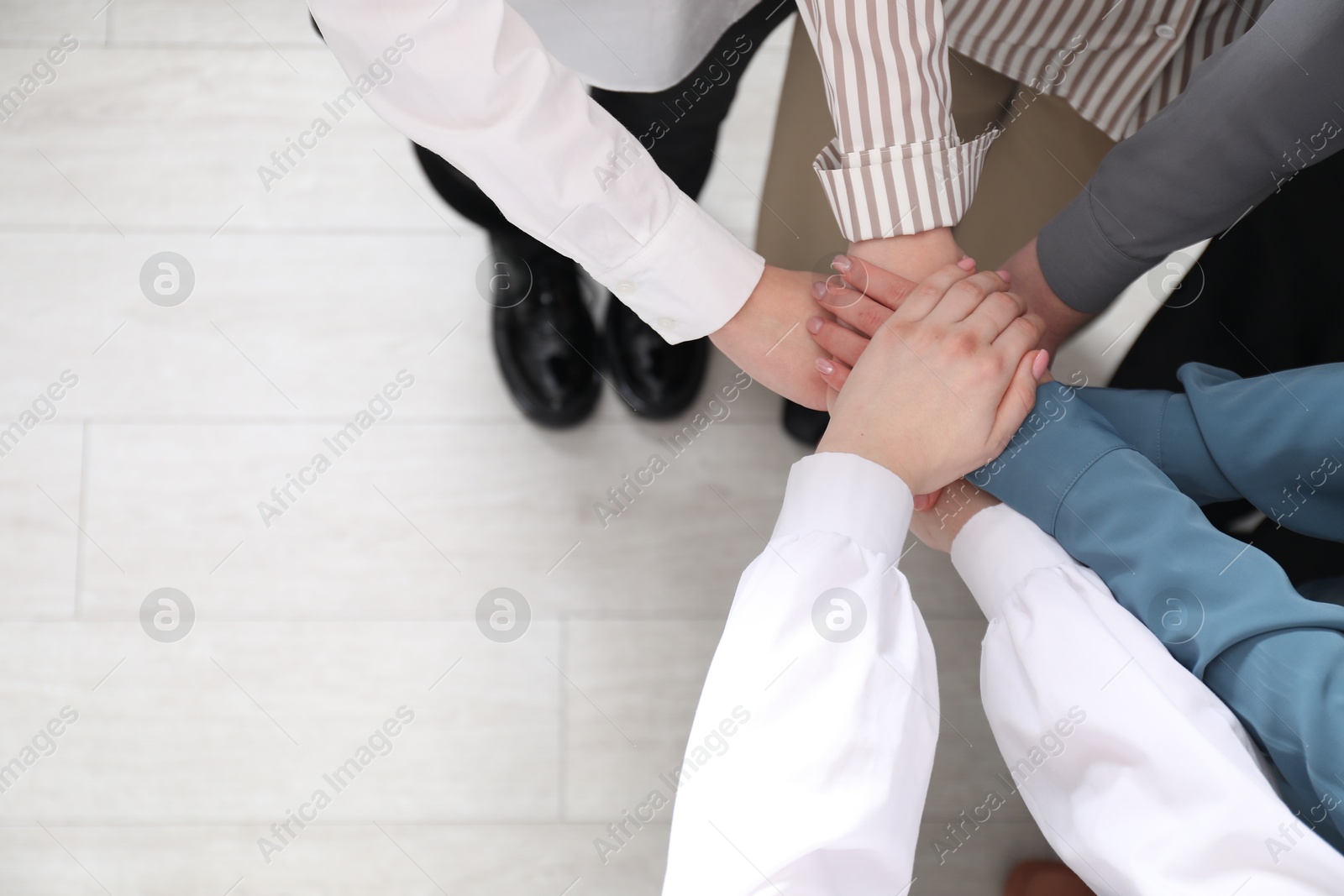 Photo of Business concept. Group of people stacking hands indoors, above view. Space for text