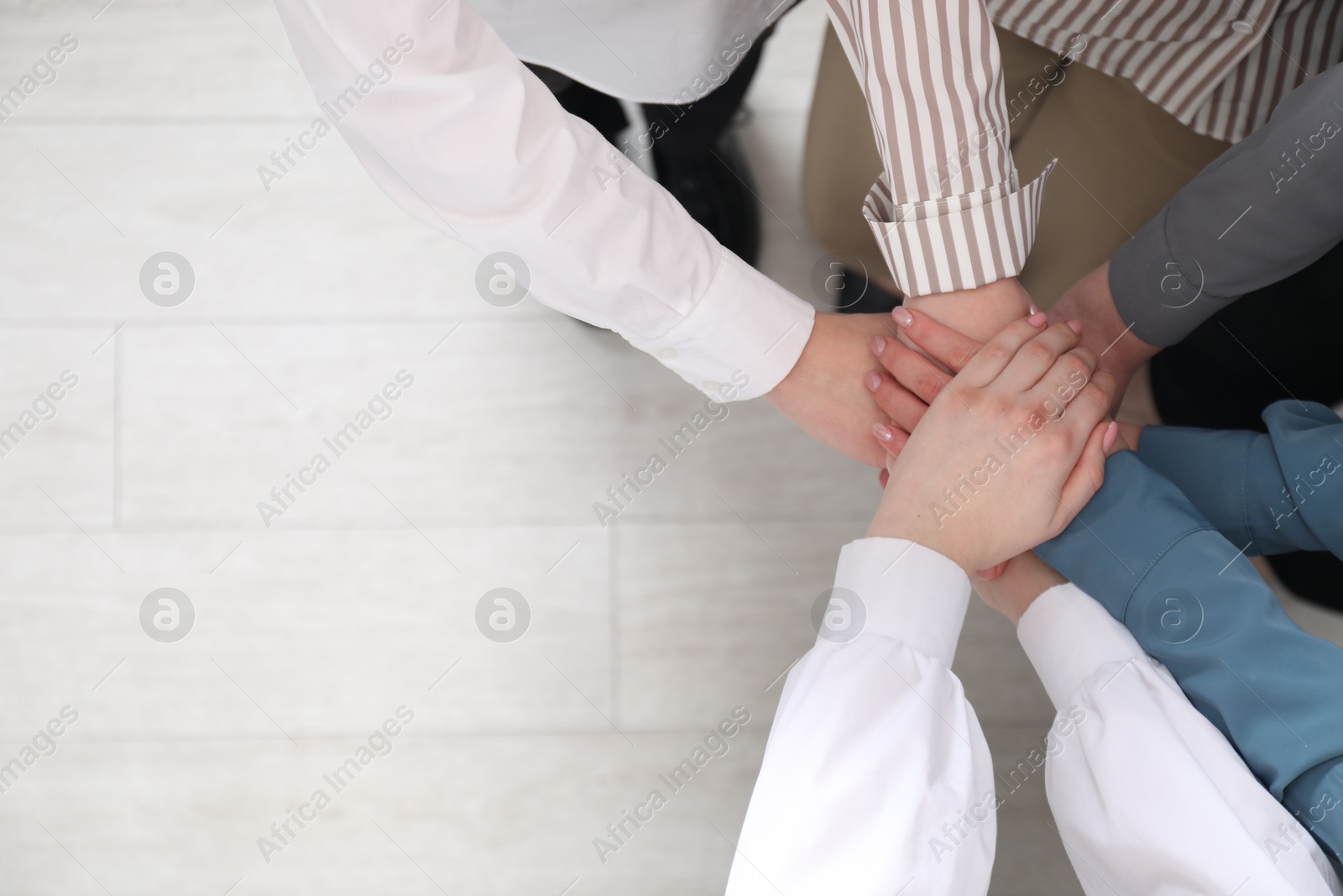 Photo of Business concept. Group of people stacking hands indoors, above view. Space for text