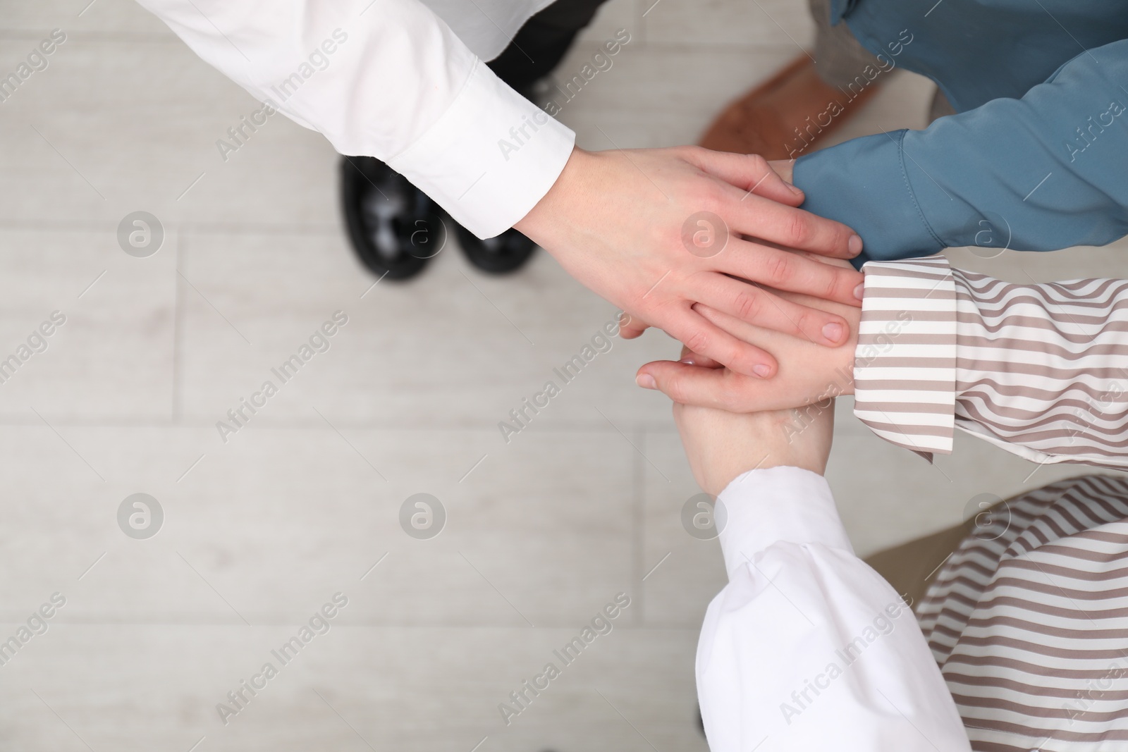 Photo of Business concept. Group of people stacking hands indoors, above view. Space for text